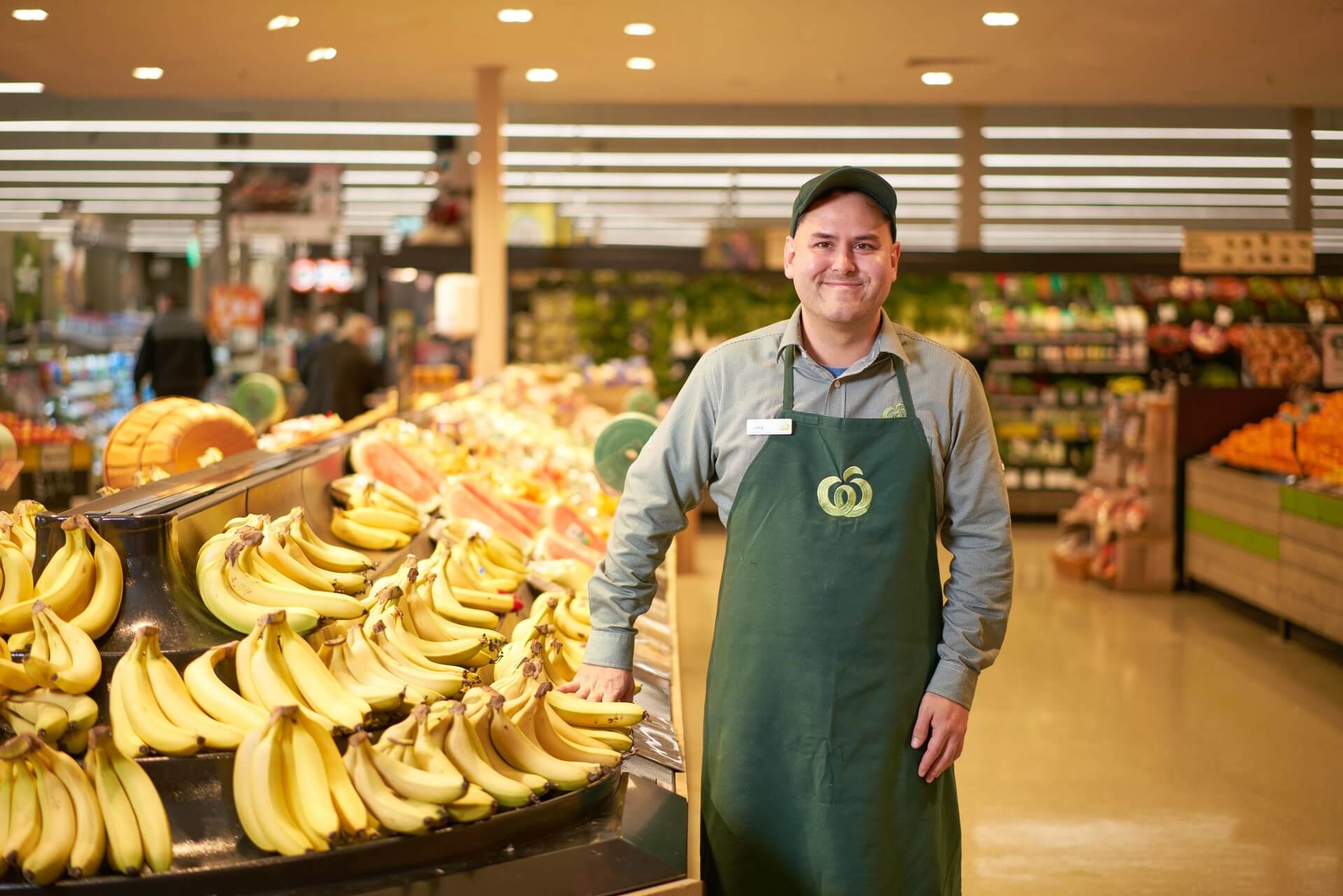 Young man who has found work at Woolworths standing next to a banana stand