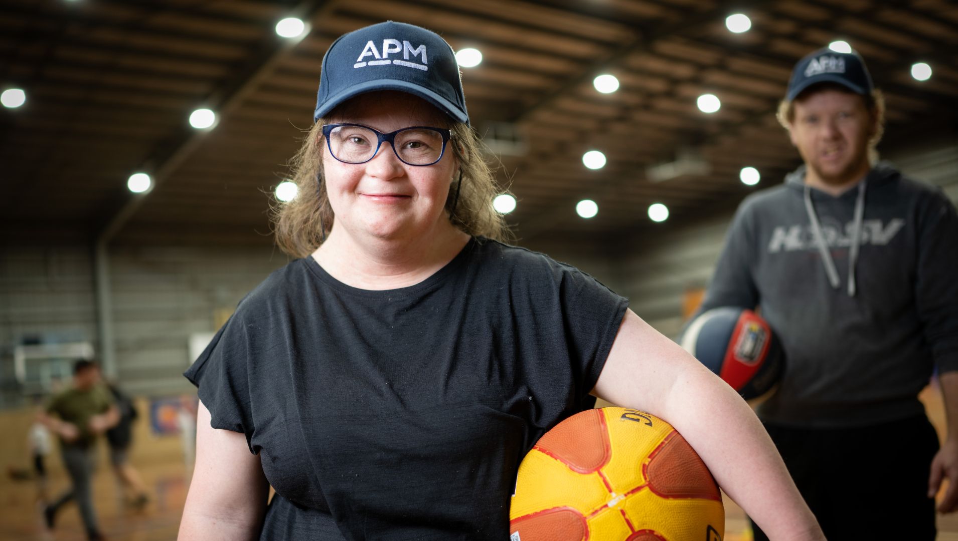 A young girl with a basketball and an APM cap